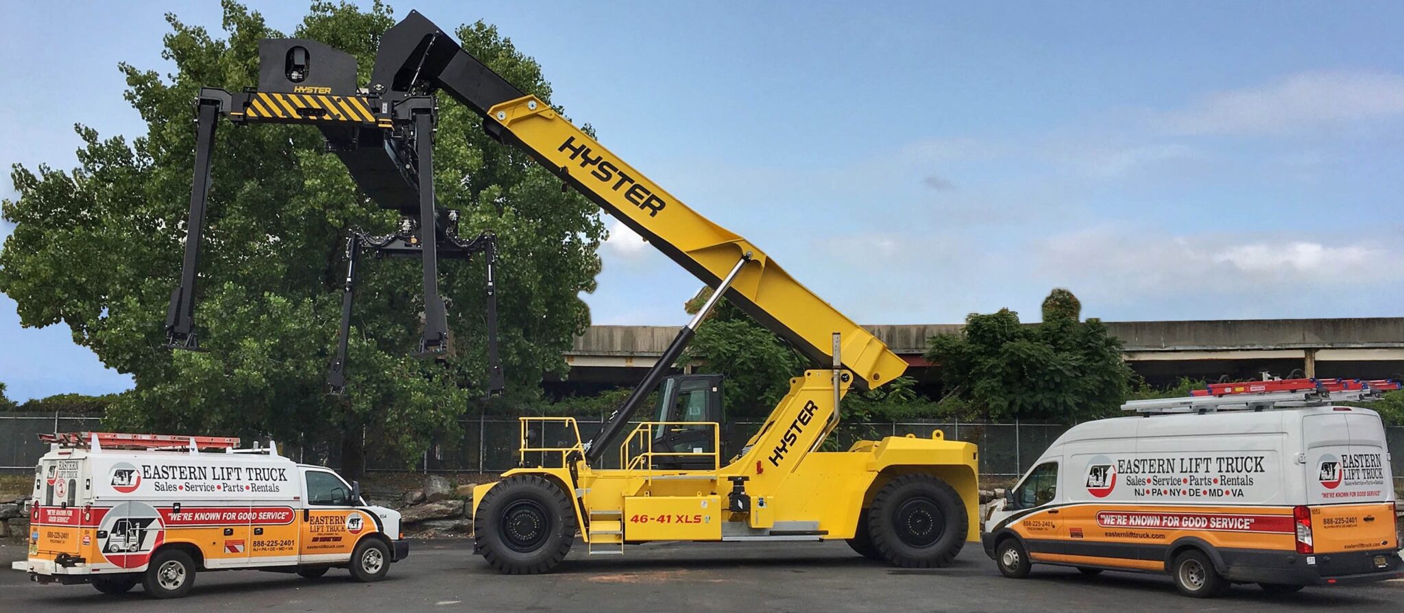 Hyster reach stacker forklift flanked by two Eastern Lift Truck Co. Service vehicles.