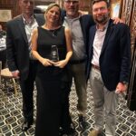 Photo of Eastern Lift Truck Co. employees, James Moore, Brandi Foley, Nick Nicolini, and Chris Minkiewicz. Brandi is holding an award for top 2024 Salesperson.