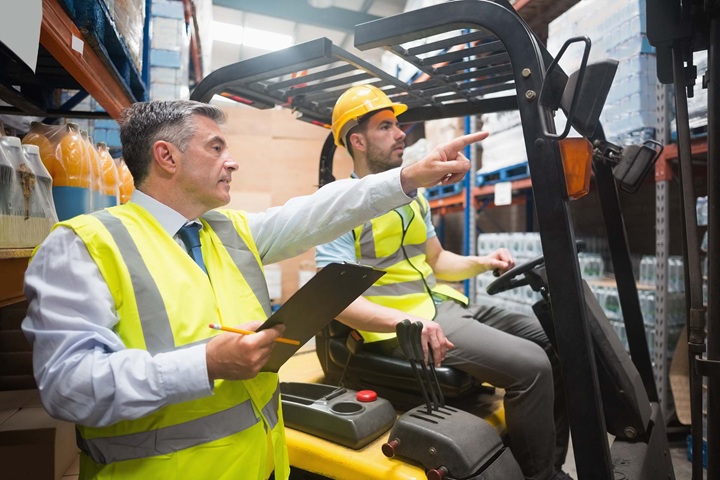 Forklift driver talking with his manager during forklift operator training course.